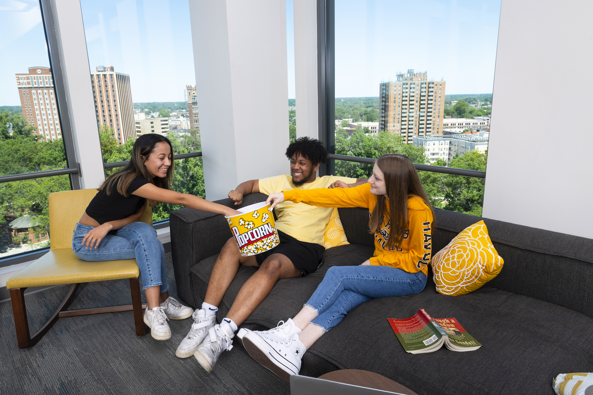 Residents sharing popcorn in a GRC common area with windows behind overlooking campus